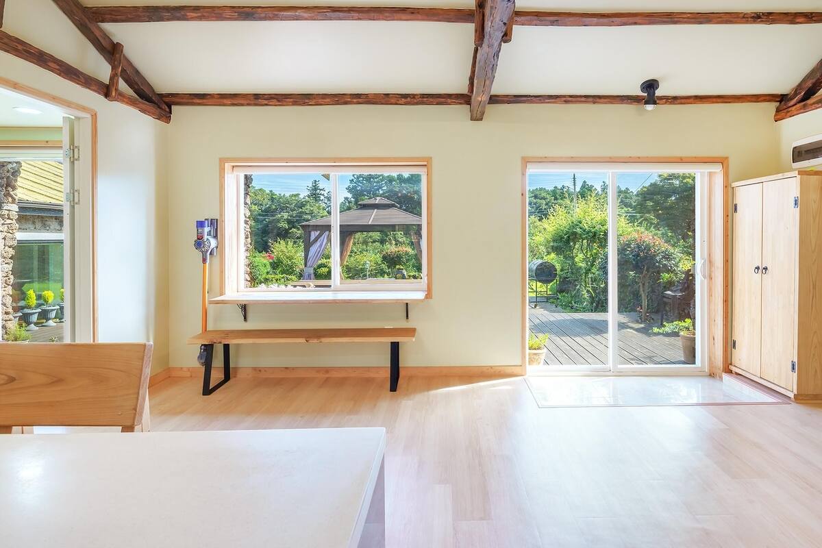 Une pièce spacieuse dotée d’un plancher en bois, d’un banc et de grandes portes-fenêtres coulissantes donnant sur un jardin.