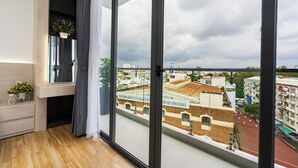 A modern apartment with large windows, a wooden floor, a small plant, and a view of the cityscape. - Haya Bac Hai Apartments (Ho Chi Minh City)