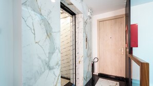 A hallway with marble walls and a wooden door. - Haya Bac Hai Apartments (Ho Chi Minh City)