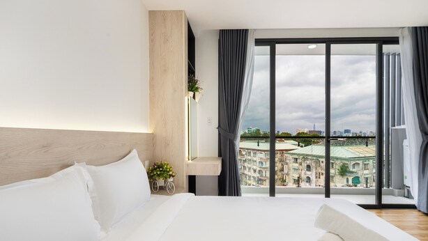 A hotel room with a large bed, a view of the cityscape through a large window, and a modern interior design. - Haya Bac Hai Apartments (Ho Chi Minh City)