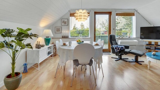 A spacious living area with a dining table, chairs, a sofa, and a TV.