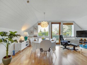 A spacious living area with a dining table, chairs, a sofa, and a TV.
