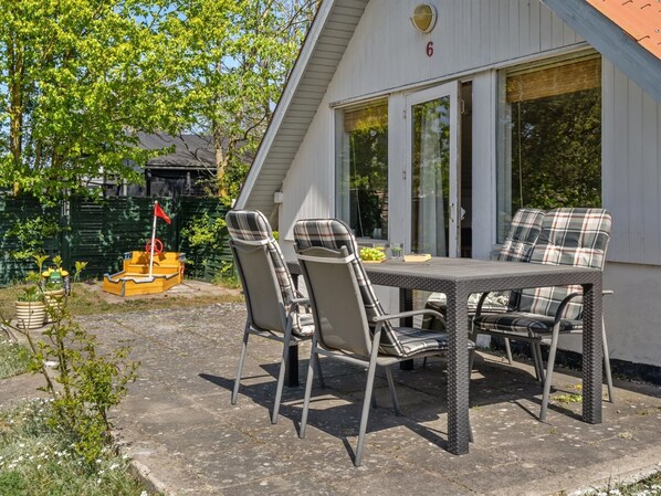 A small, single-story building with a patio area featuring a table and four chairs.