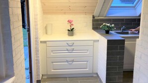 A compact kitchen with white cabinetry, a skylight, and a small countertop with flowers.