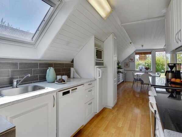 A modern kitchen with white cabinetry, a skylight, and a view of the outdoors.