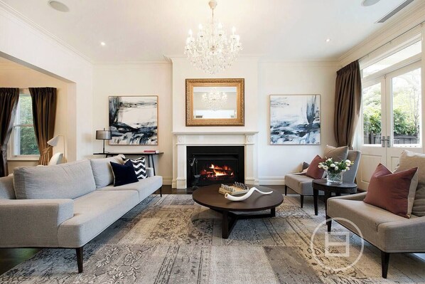 A living room with a fireplace, two sofas, a coffee table, and artwork on the walls. - Inner City Resort (St Kilda)