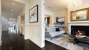 A spacious living room with a fireplace, a chandelier, and a sofa. - Inner City Resort  (St Kilda)