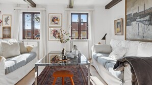 Ein Wohnzimmer mit zwei weißen Sofas, einem Glastisch und einem gemusterten Teppich.