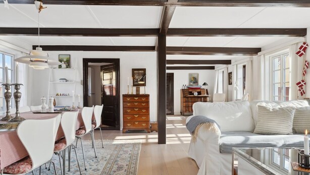 Ein geräumiges Wohnzimmer mit einem weißen Sofa, einem Essbereich mit Tisch und Stühlen sowie einer Holzkommode.