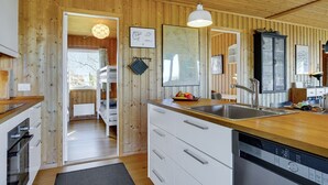 A modern kitchen with wooden walls, white cabinets, and a stainless steel sink. - "Iadrik" - 85m to the fjord by Interhome (Skibby)