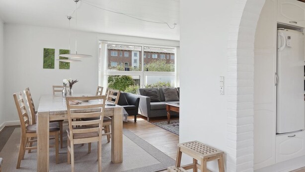 A modern kitchen with white cabinetry, a built-in oven, and a window overlooking a garden.