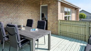 A patio with a table and chairs, a brick wall, and a wooden fence.