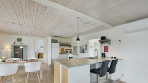 Een moderne keuken met een centraal eiland, barstoelen en hanglampen.