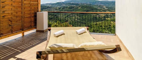Ein Balkon mit Holzboden, eine Holzhütte und Blick auf eine gebirgige Landschaft.