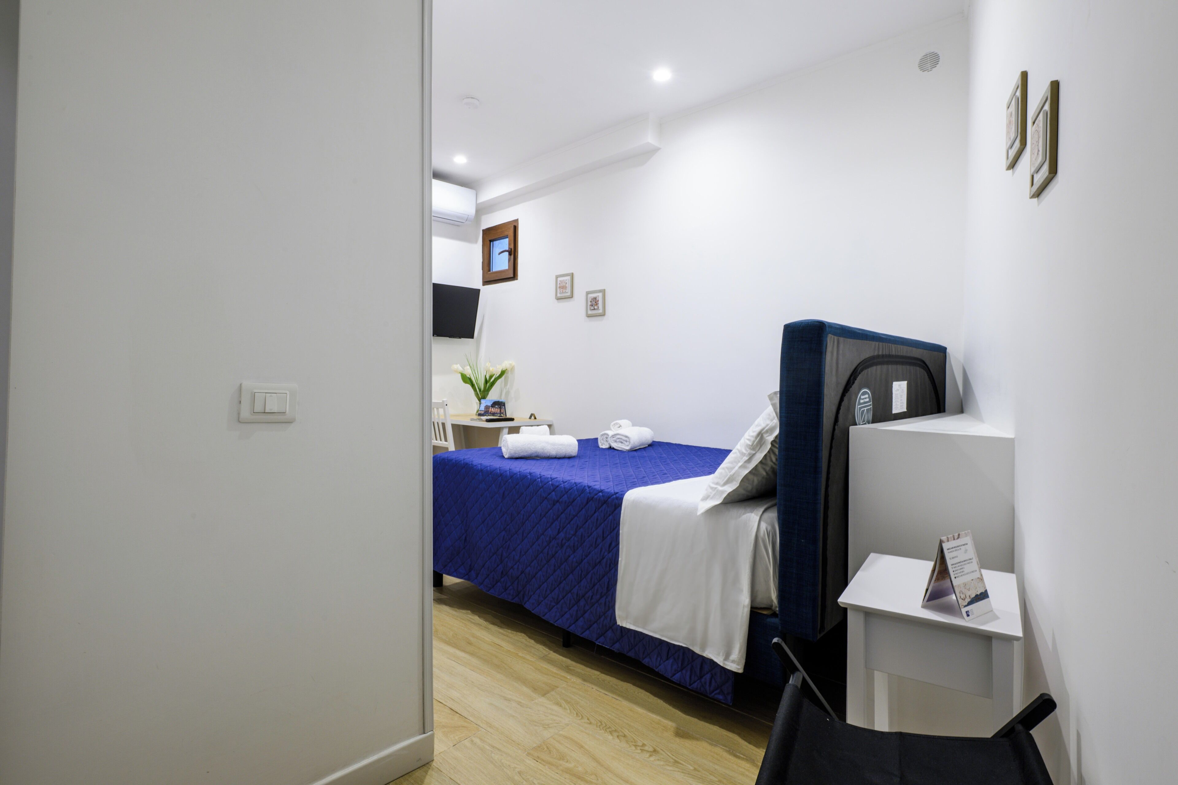 A hotel room with a bed, a desk, a chair, and a small table.
