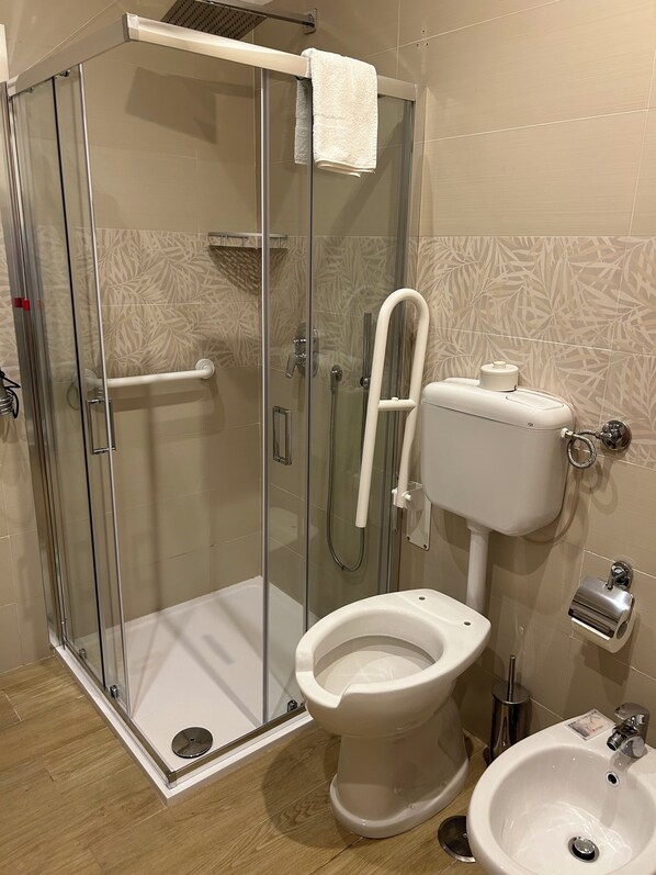 Un baño con ducha de vidrio, inodoro y lavamanos.