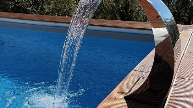 Une piscine dotée d’un élément décoratif aquatique moderne aux lignes courbes.