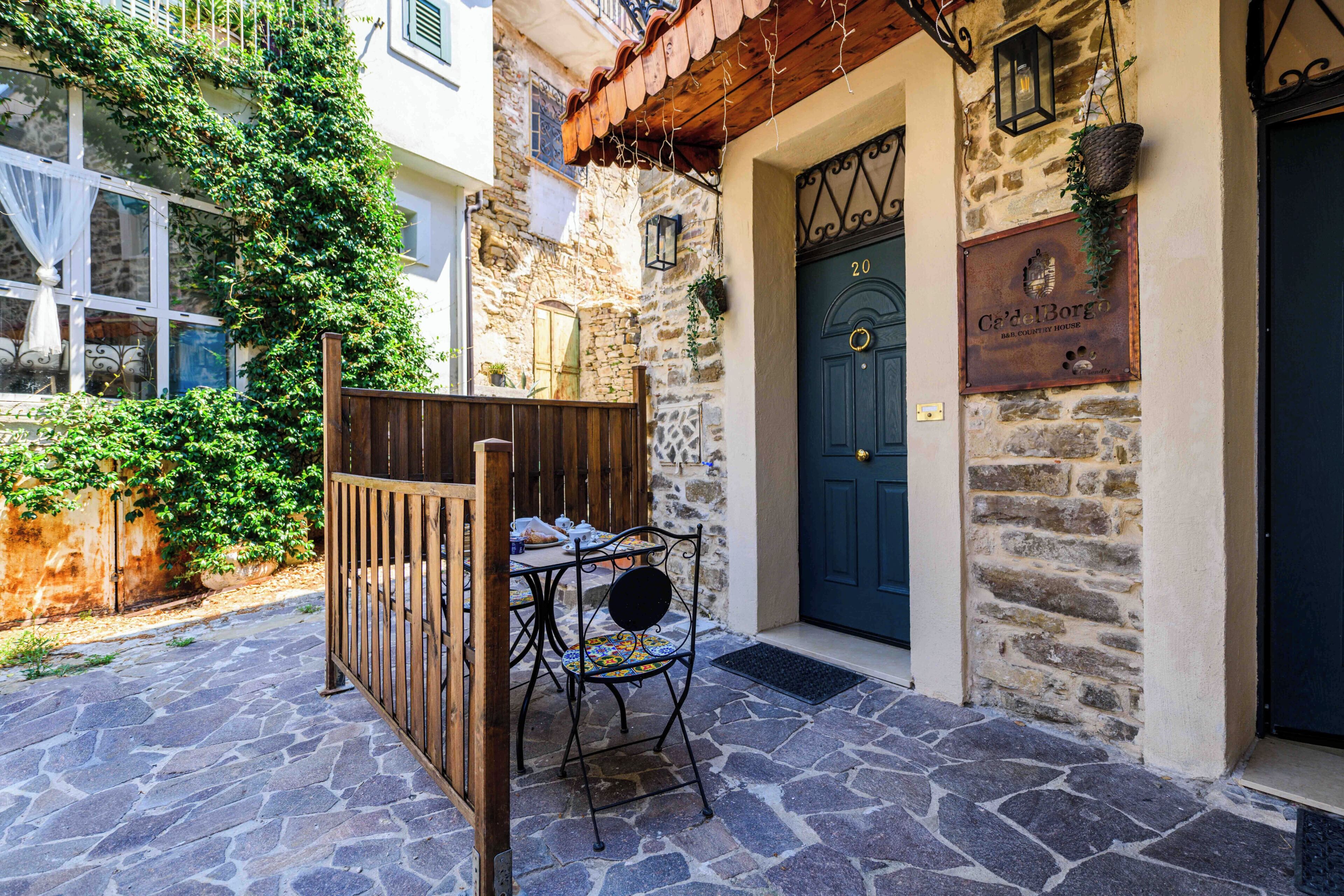 Un edificio rustico in pietra con una porta in legno con la scritta 'Ca'delBorgo B&B Country House'.
