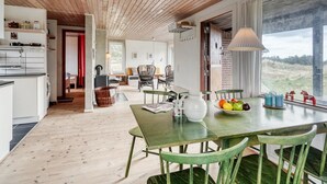 A spacious room with a wooden ceiling, a dining area with a table and chairs, and a view through a large window. - "Thorgisl" - 1.4km from the sea by Interhome (Blåvand)