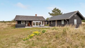 A modern house with a large glass door entrance, a small attached garage, and a patio area with outdoor seating. - "Thorgisl" - 1.4km from the sea by Interhome (Blåvand)