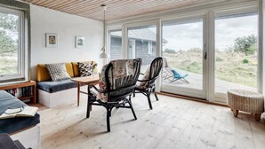 A cozy living room with a wooden ceiling, a sofa with cushions, two wicker chairs, a small table, and a bookshelf. - "Thorgisl" - 1.4km from the sea by Interhome (Blåvand)