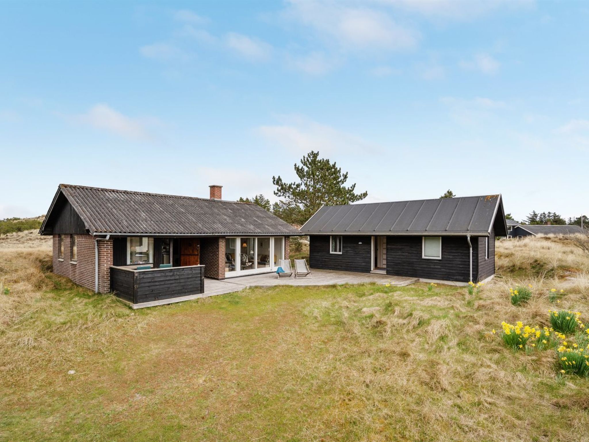 A modern two-story house with a flat roof, large windows, and a patio area.
