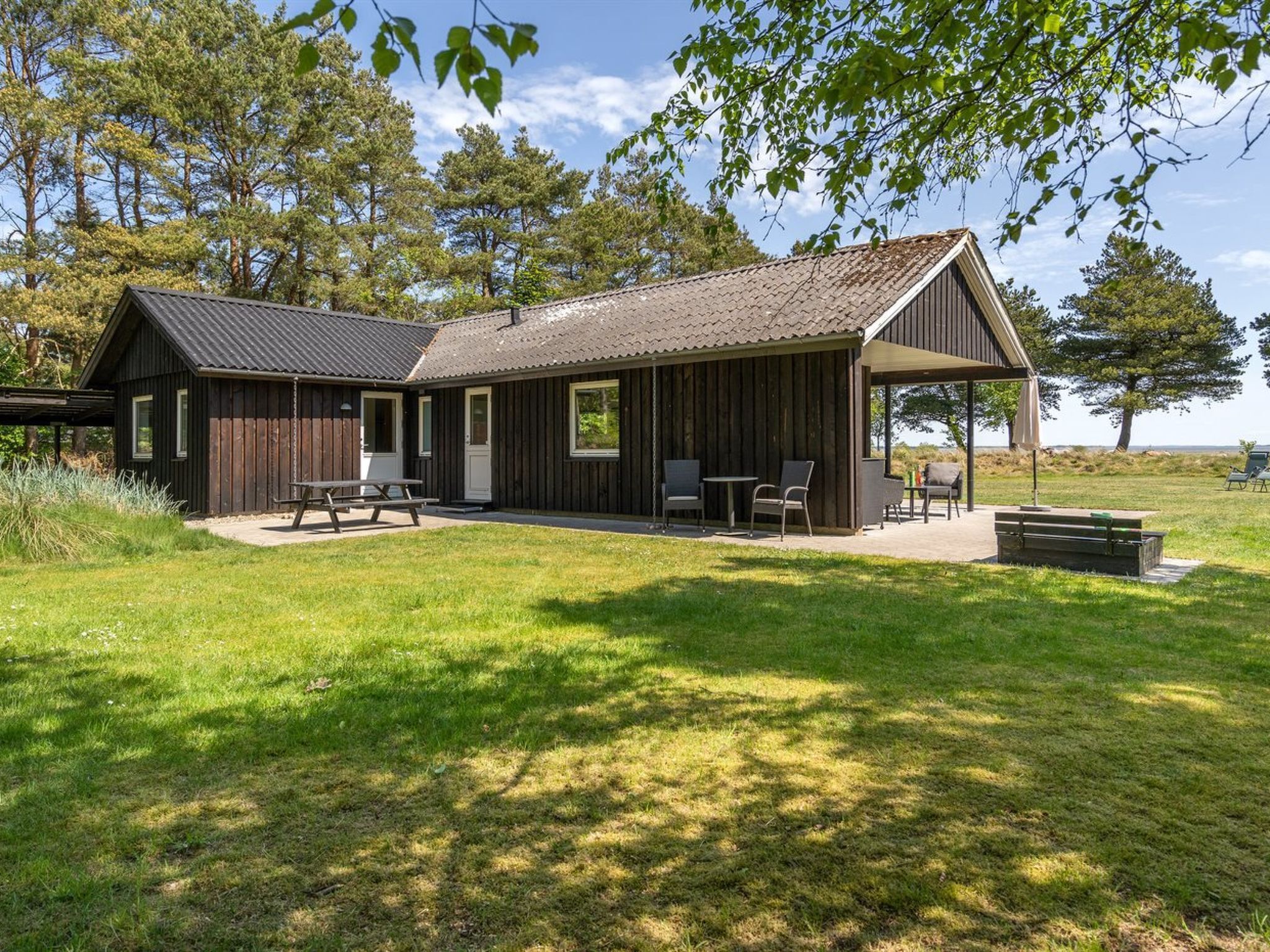 A rustic cabin with a covered patio, picnic table, and outdoor seating area.
