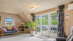 A cozy living room with a sofa, a coffee table, and a large window overlooking a garden.