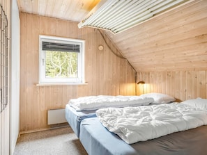 Ein Zimmer mit Holzwänden, einem Bett, einem Fenster und einer Heizung.