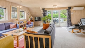 A spacious living area with a sofa, armchair, and a television.