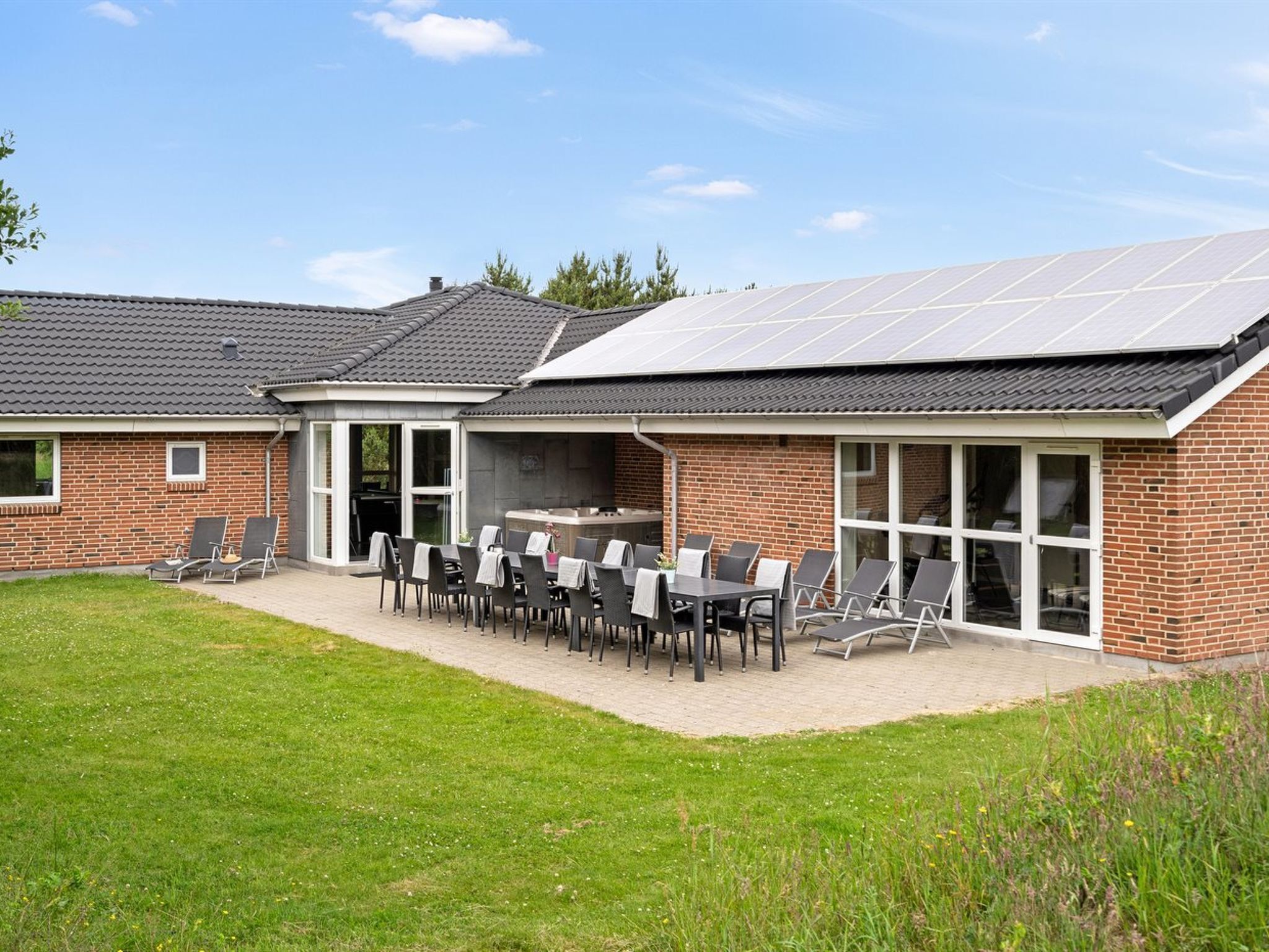 Ein Haus mit Terrasse, Sitzgelegenheit im Freien und einer Solaranlage.