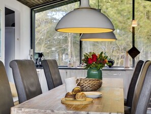 Een eetgedeelte met een houten tafel, lederen stoelen, een vaas met bloemen en een koffieapparaat.