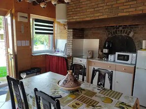 Una cocina con pared de ladrillo, ventana, microondas y mesa con sillas.