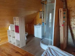 Una habitación pequeña con cama, ducha y baño reducido.