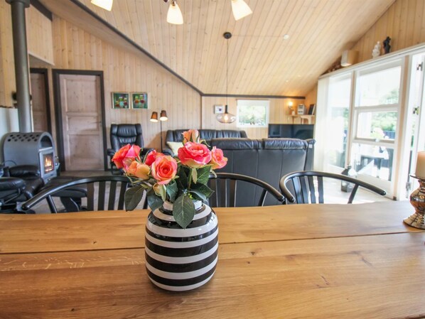 Ein Holzinterieur mit Esstisch, Stühlen, Kamin und einem großen Fenster.