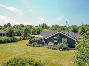 A residential property with a well-maintained lawn, a patio with outdoor furniture, and a small shed.