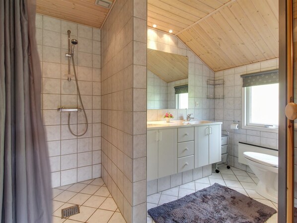A modern bathroom with a shower, toilet, sink, and cabinets.