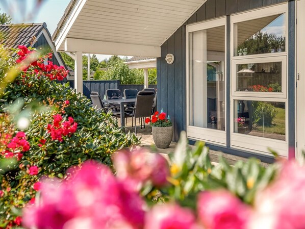 A covered patio area with outdoor furniture and a large sliding glass door leading to a garden.