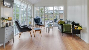 A spacious living room with a grey sofa, black armchairs, and a coffee table. There is a TV mounted on the wall and a window providing natural light. - "Riekje" - 2.3km from the sea by Interhome (Rømø)