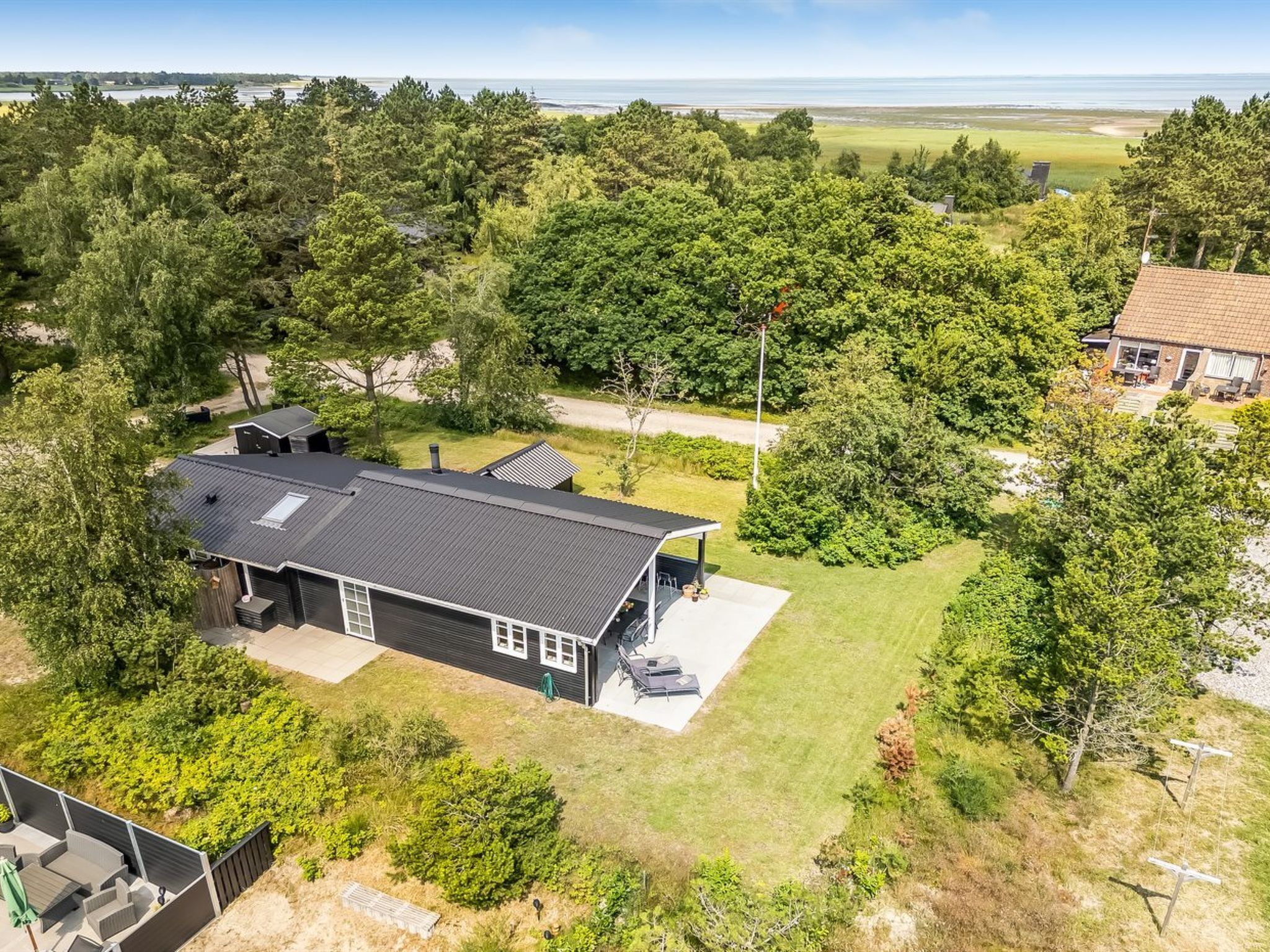 A residential property with a large house, a covered patio, and a view of a body of water.