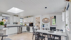 A modern kitchen with white cabinetry, a central island, and a dining area with a table and chairs. - "Riekje" - 2.3km from the sea by Interhome (Rømø)