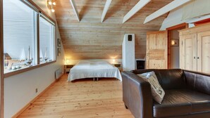 Une pièce chaleureuse avec un lit, un canapé en cuir, un plancher en bois et de grandes fenêtres.