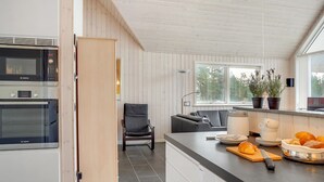 A modern kitchen with built-in Bosch appliances, a grey sofa, and a dining area with a wooden table and potted plants. - "Lima" - 3.5km from the sea by Interhome (Rømø)