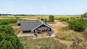 Een modern huis met een schuin dak, een terras met tuinmeubilair en uitzicht op het omliggende landschap.