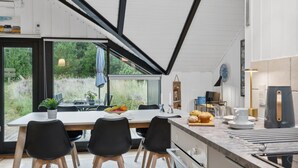 Een moderne keuken met een groot keukeneiland, zwarte stoelen en uitzicht op groen.