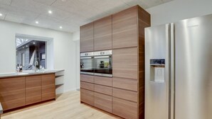 A modern kitchen with wooden cabinetry, stainless steel appliances, and a large window.