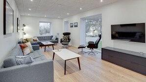 A modern living room with a grey sofa, a coffee table, and a TV mounted on the wall.