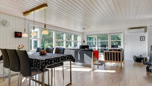 Cozinha moderna com área de refeições, janelas amplas e piso de madeira.