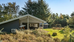 Uma casa moderna com varanda coberta, baloiço e jardim.