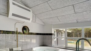 A bathroom with a bathtub, a window, and a view of a pool.